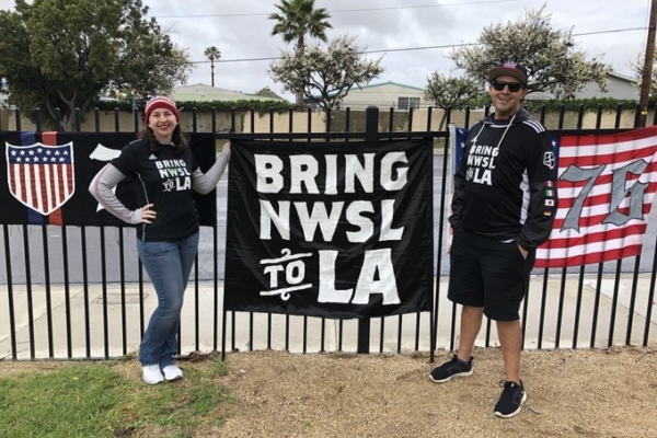 Mark and Lindsay Rojas stand with a "Bring NWSL to LA" flag