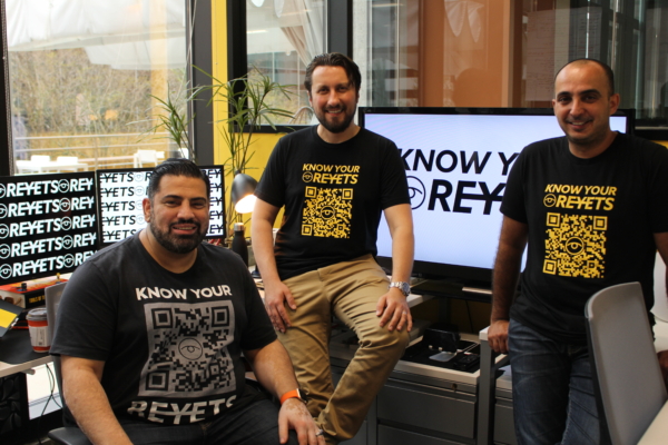 The three cofounders of Reyets pose in their office in branded tshirts.