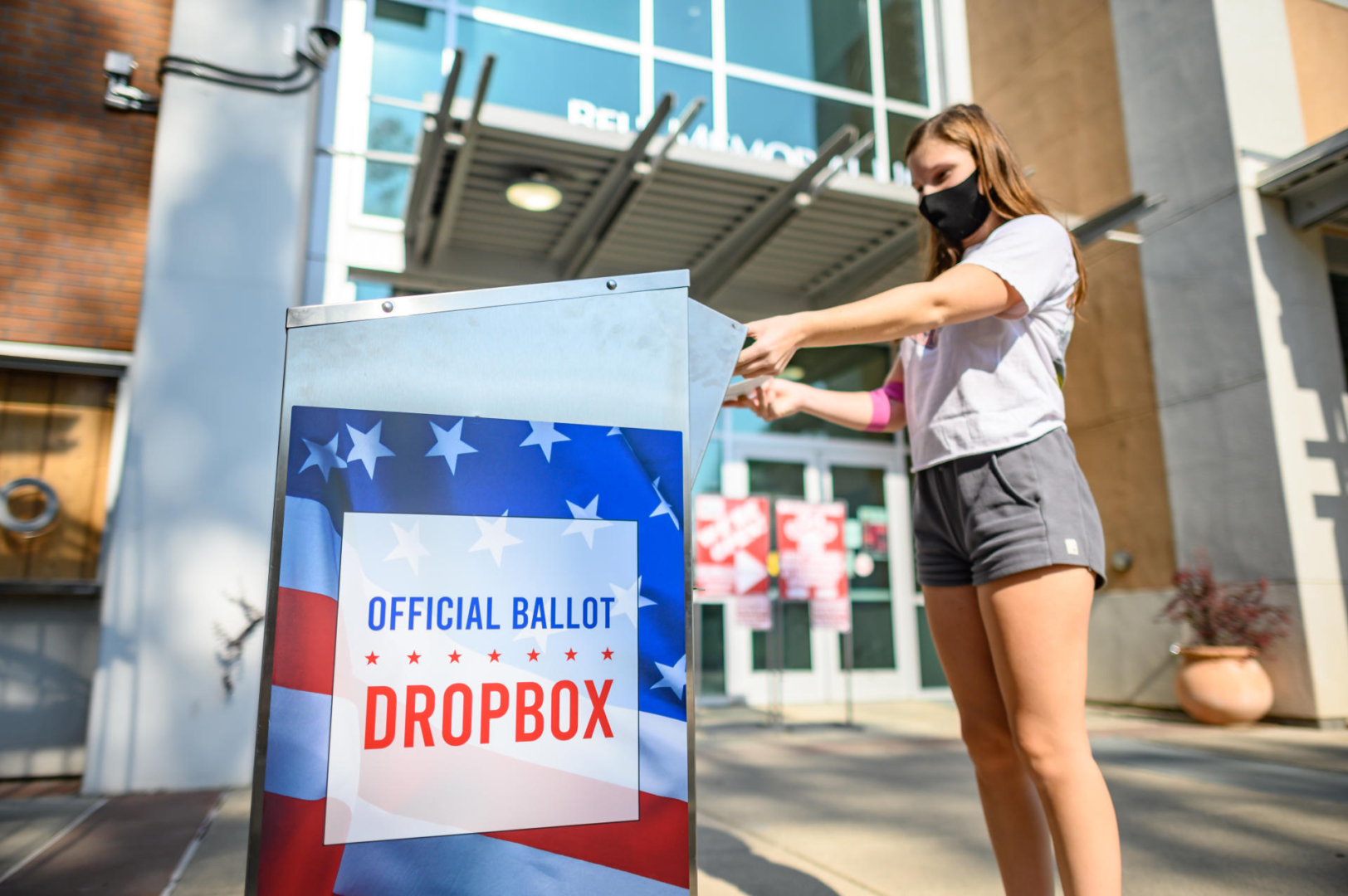 A student drops a ballot in an official drop box in front of the Bell Memorial Union. 
