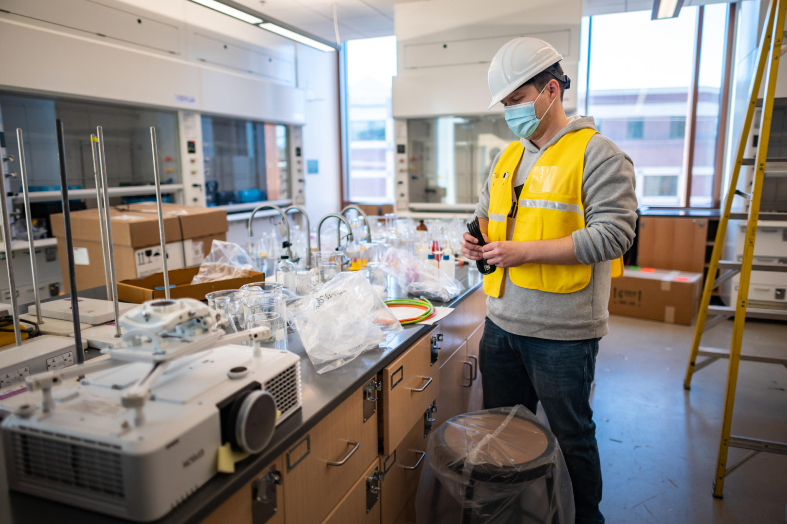A person in a hard hat unwraps lab technology such as beakers and other tools in a new laboratory classroom.