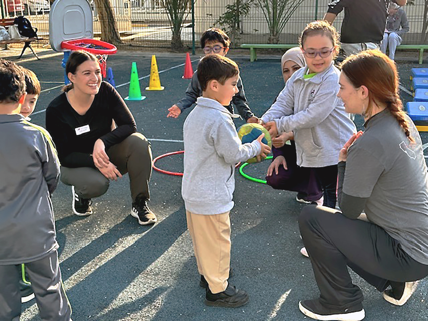 Chico State students and educators interact with children on a playground at a school in the UAE.