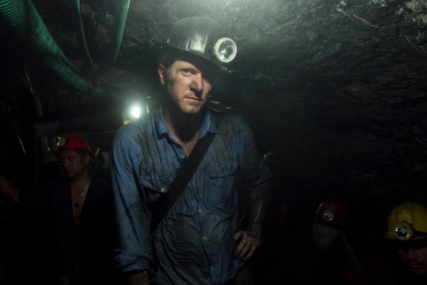 Brian Brazeal wears a helmet with a headlamp in a dark mine shaft.