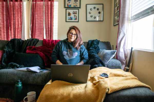 Irene Echavarria sits on her couch with her laptop open in front of her.