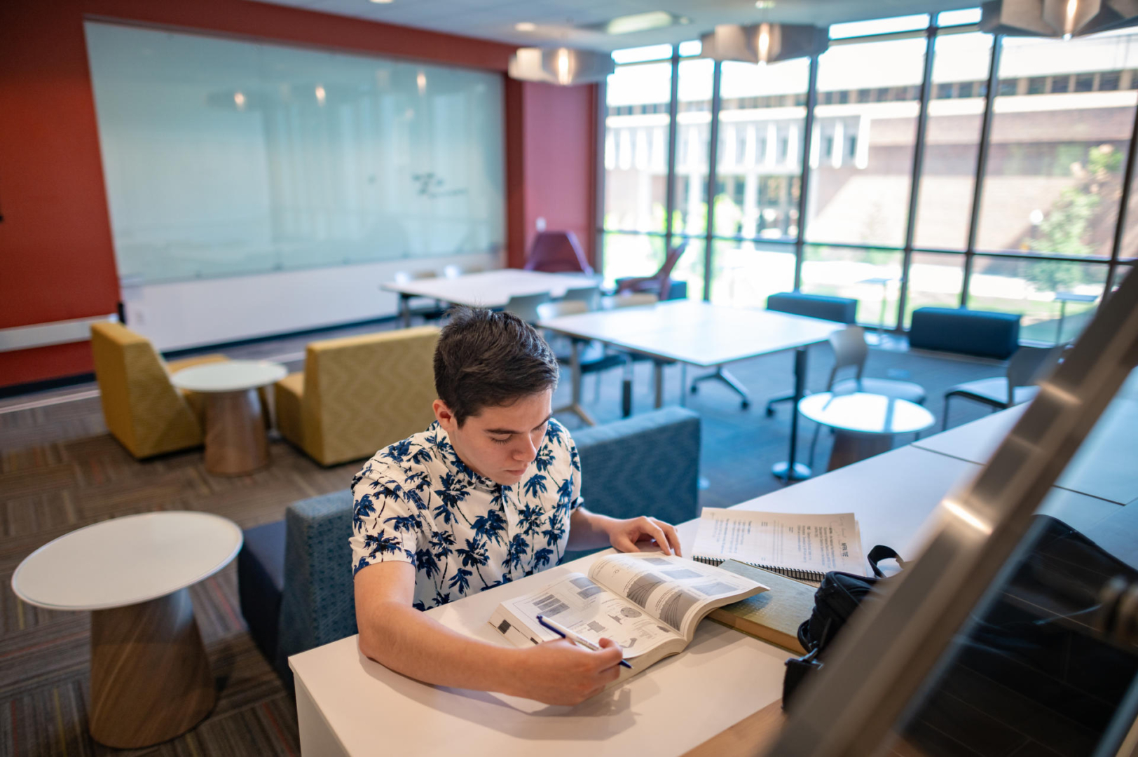 A student sits at a raised counter in a group seating area in the new Science Building.