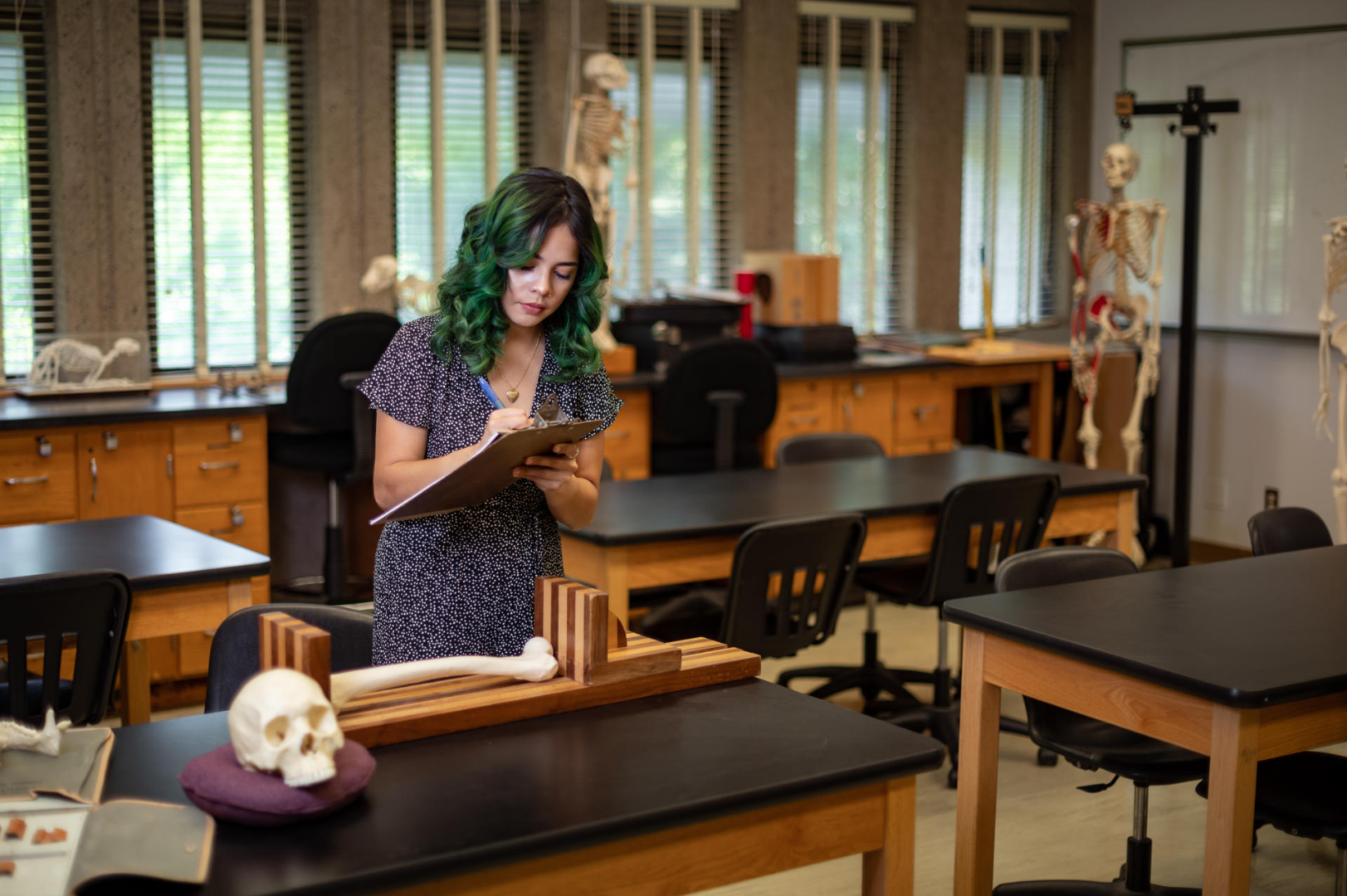 Daisy Linsangan writes on a clipboard near a table with model human remains.