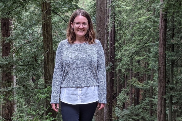 Sarah Moschetti standing in front of redwood trees in the forest.