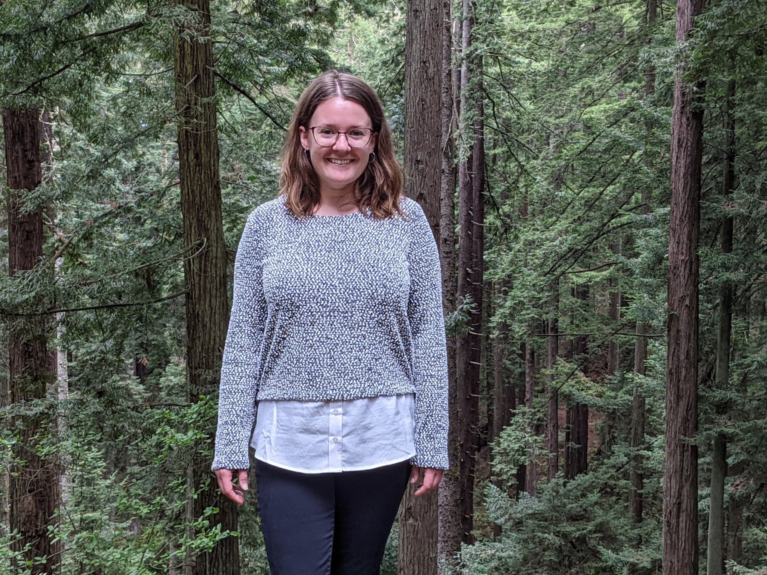 Sarah Moschetti standing in front of redwood trees in the forest.
