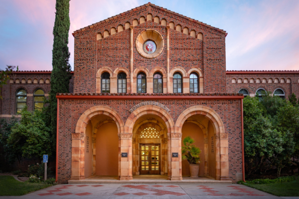 The brick facade of an academic building with three arches in the front