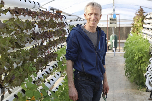 Lee Altier stands among the plants in the aquaponics garden at the University Farm