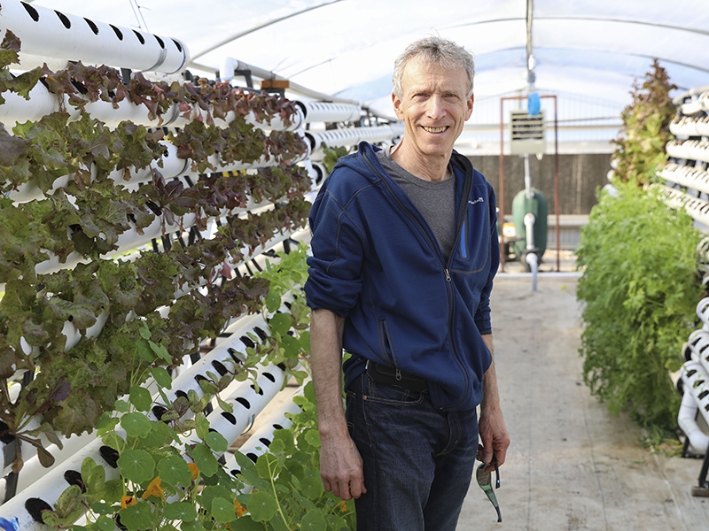 Lee Altier stands among the plants in the aquaponics garden at the University Farm