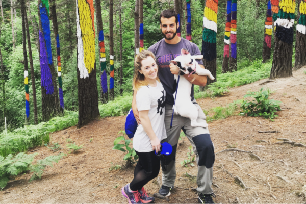 Lindsay Woychick, her husband, and french bulldog pose in a colorful forest in Spain.