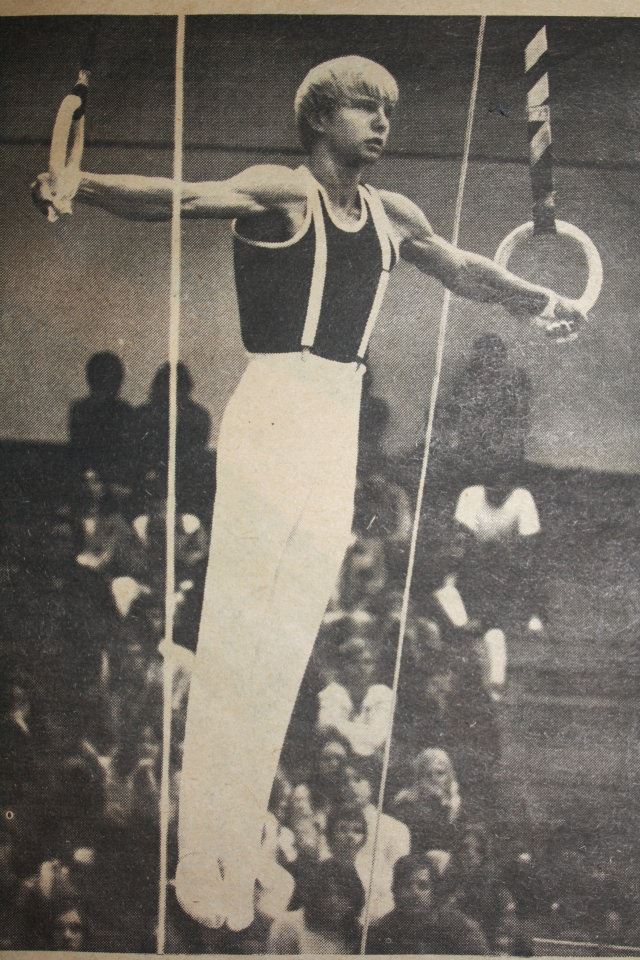 A black and white photo of a male gymnast on the rings.