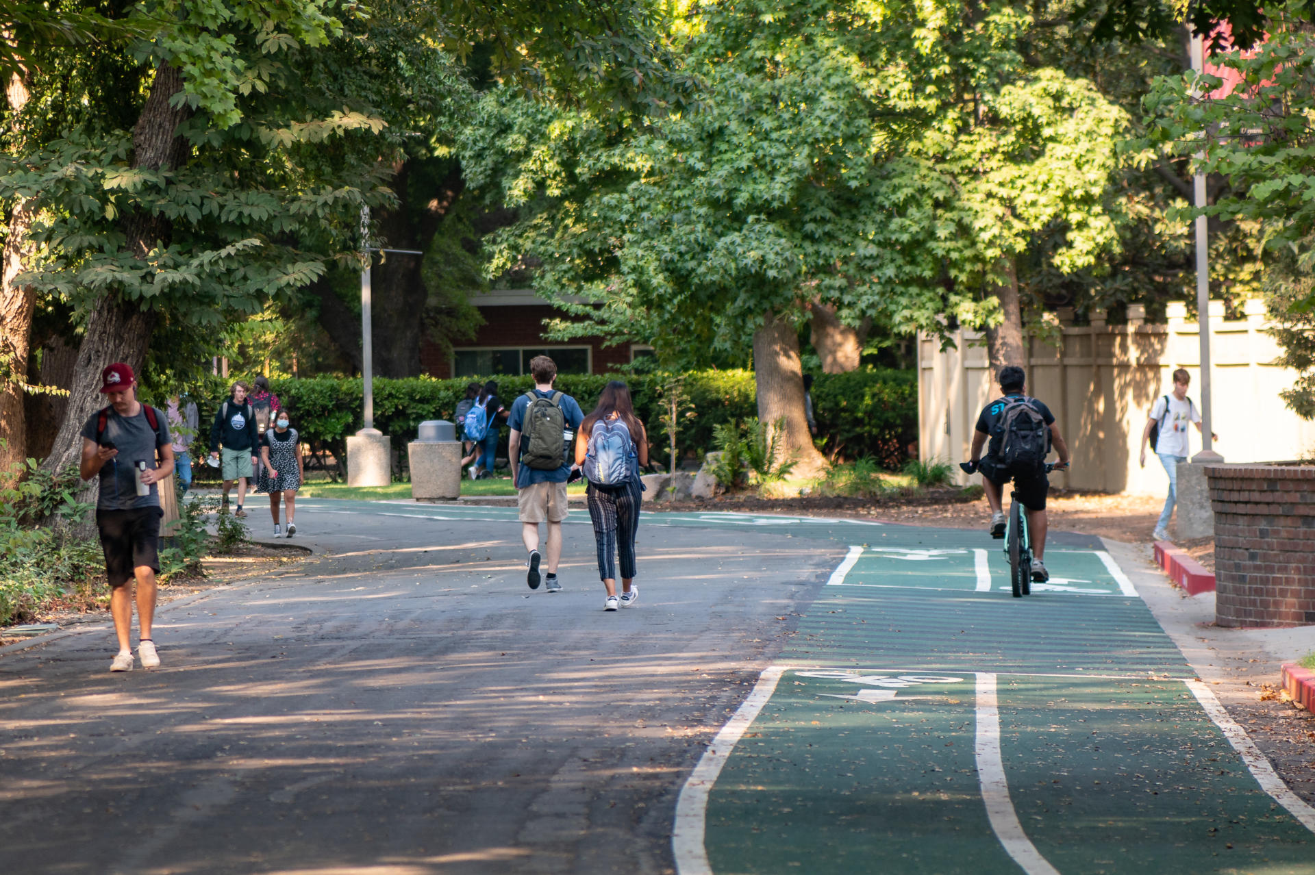 Students walk and ride bicycles on a college campus.