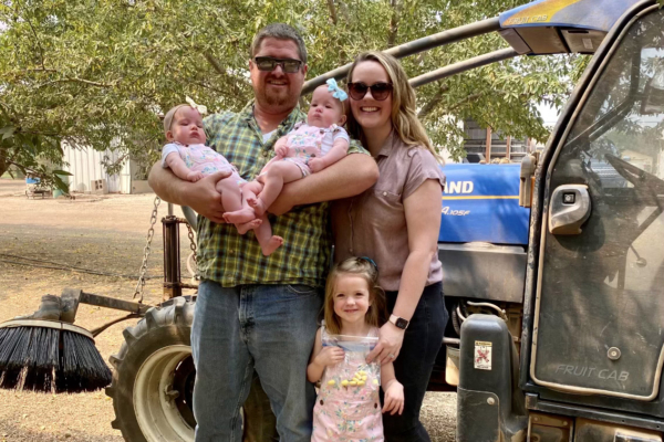 Derek Sohnrey, his wife, and three daughters stand with harvesting equipment.