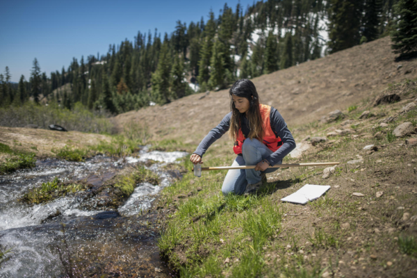 Angelica Rodriguez collects water samples along a stream in the mountains.
