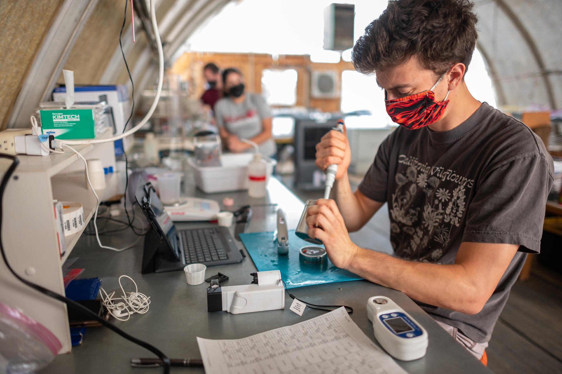 Constantin Raether, wearing a mask and squeezing a syringe, works in the RAD Lab and Soil Preparation Area at the University Farm.
