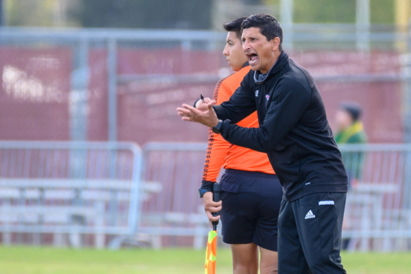 Felipe Restrepo coaches his players from the sidelines of a soccer game.
