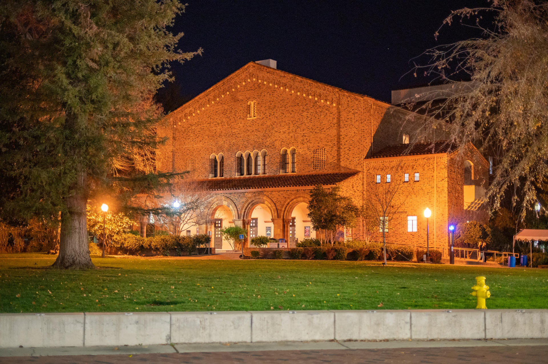 Lights illuminate the exterior of an academic building on a college campus.