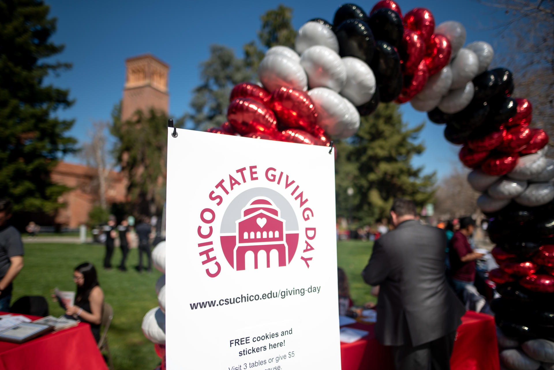A banner reading "Chico State Giving Day" sits in front of a balloon arch outside.