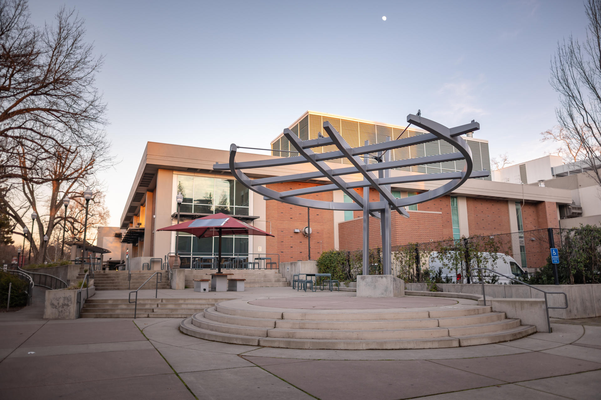 A stylish structure stands on an elevated surface outside a building on a college campus.