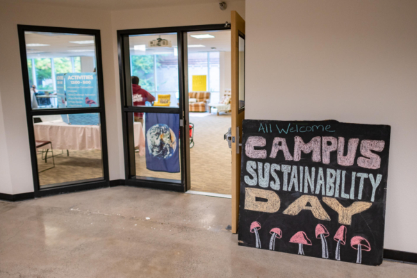 A sign outside a large room on a college campus reads "Campus Sustainability Day"