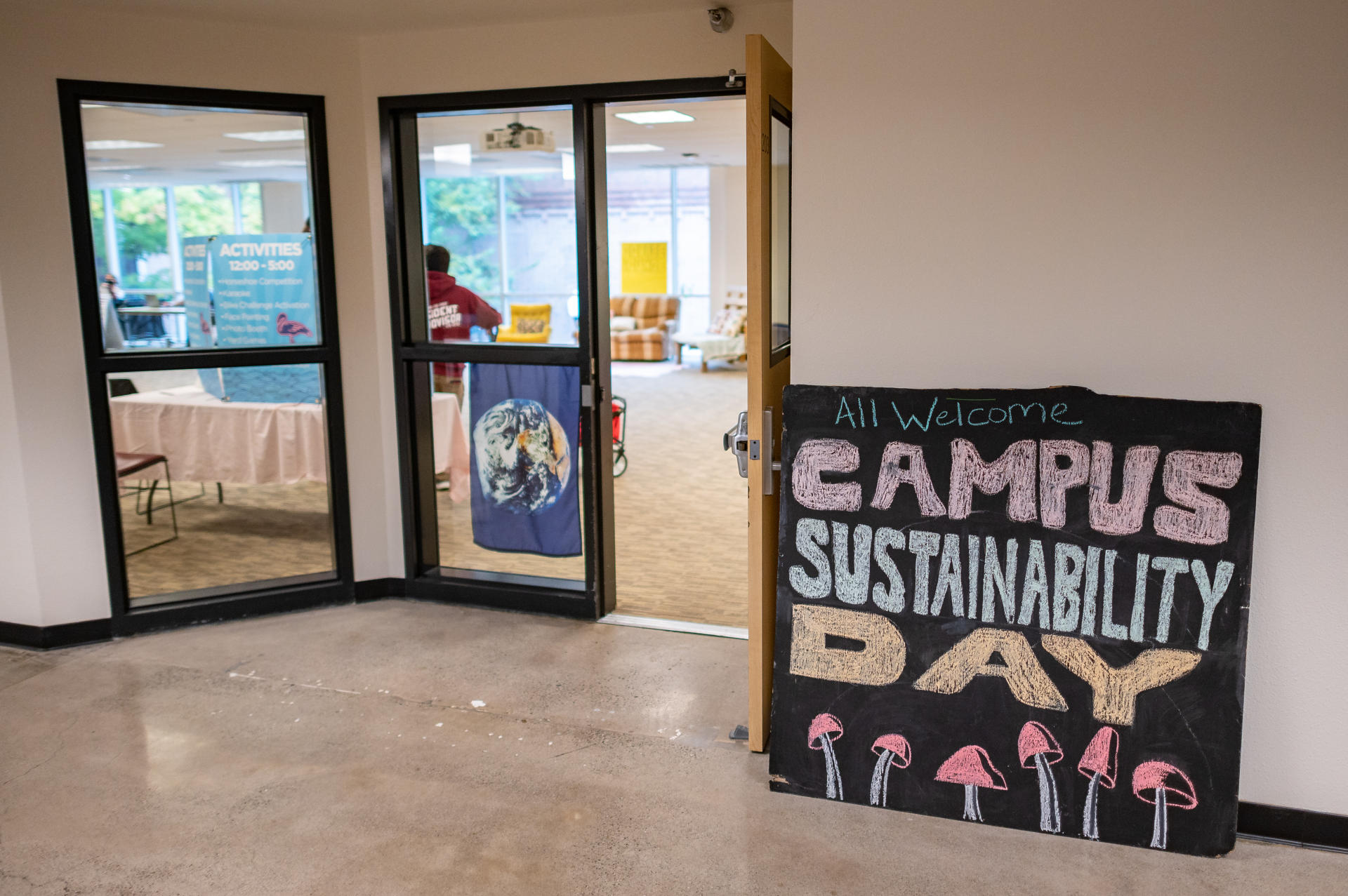 A sign outside a large room on a college campus reads "Campus Sustainability Day"