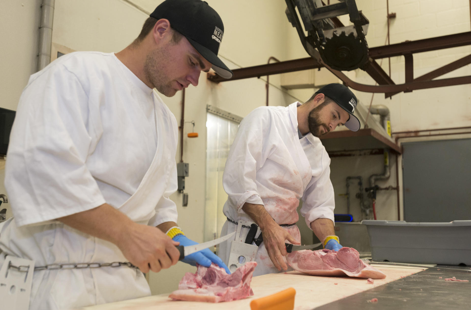 Two people butcher meat at the Meats Lab