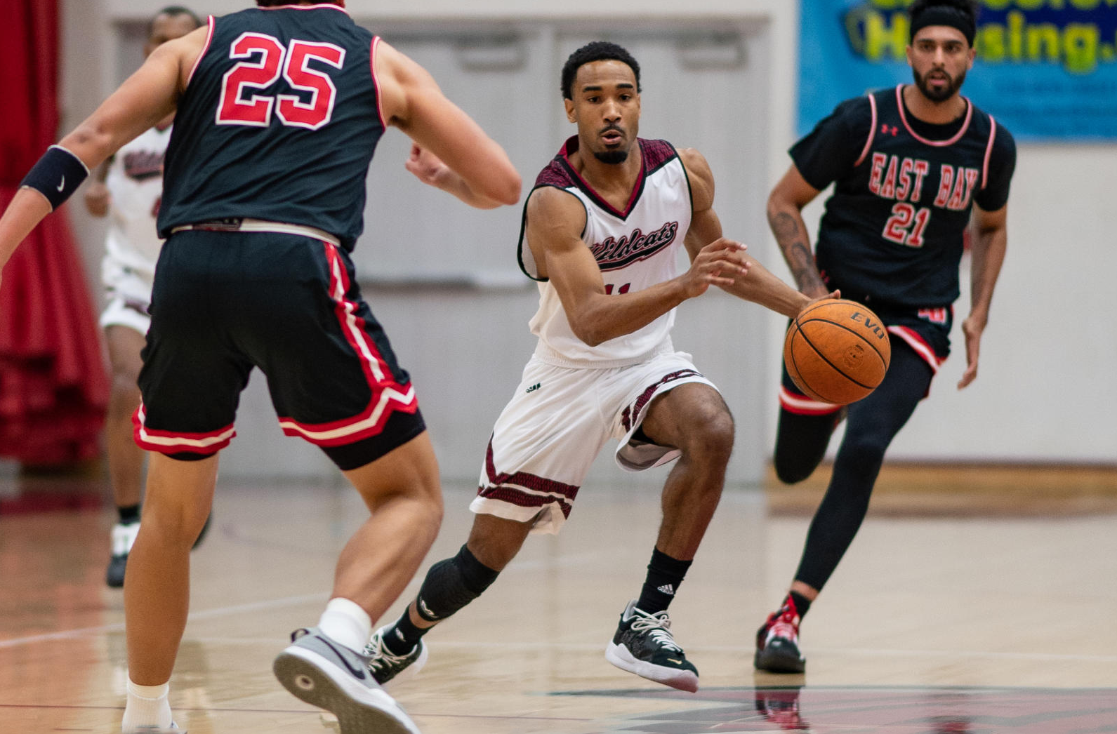 Kevin Warren dribbles between two members of the Cal State East Bay team.