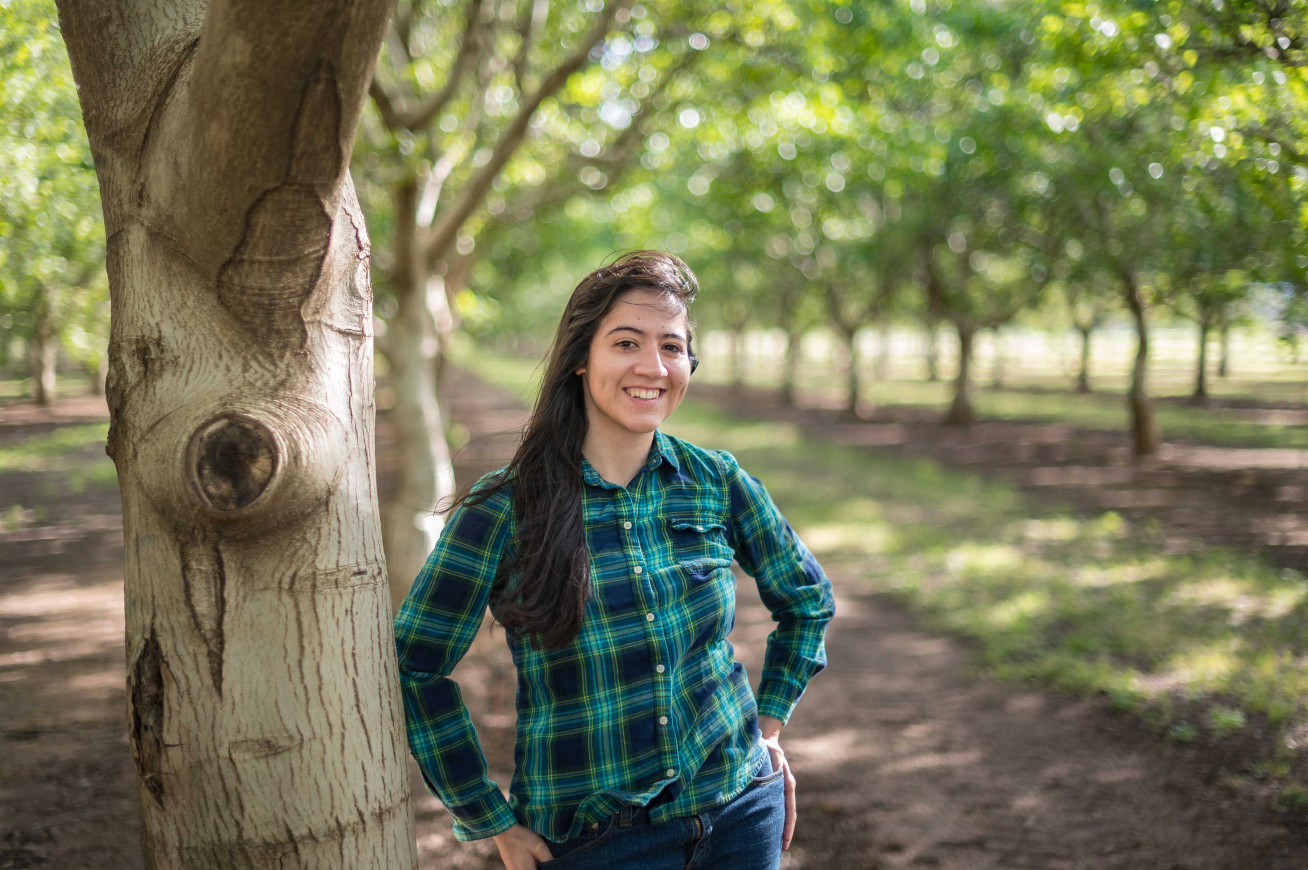 Consuelo Baez Vega leans against a walnut tree in an orchard at University Farm