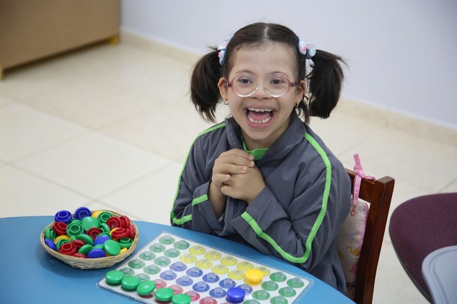 A young child clasps her hands in joy as she plays with a game.