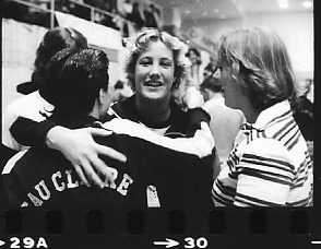 a black and white photos shows members of the 1980s swim team embrace at the national competition.