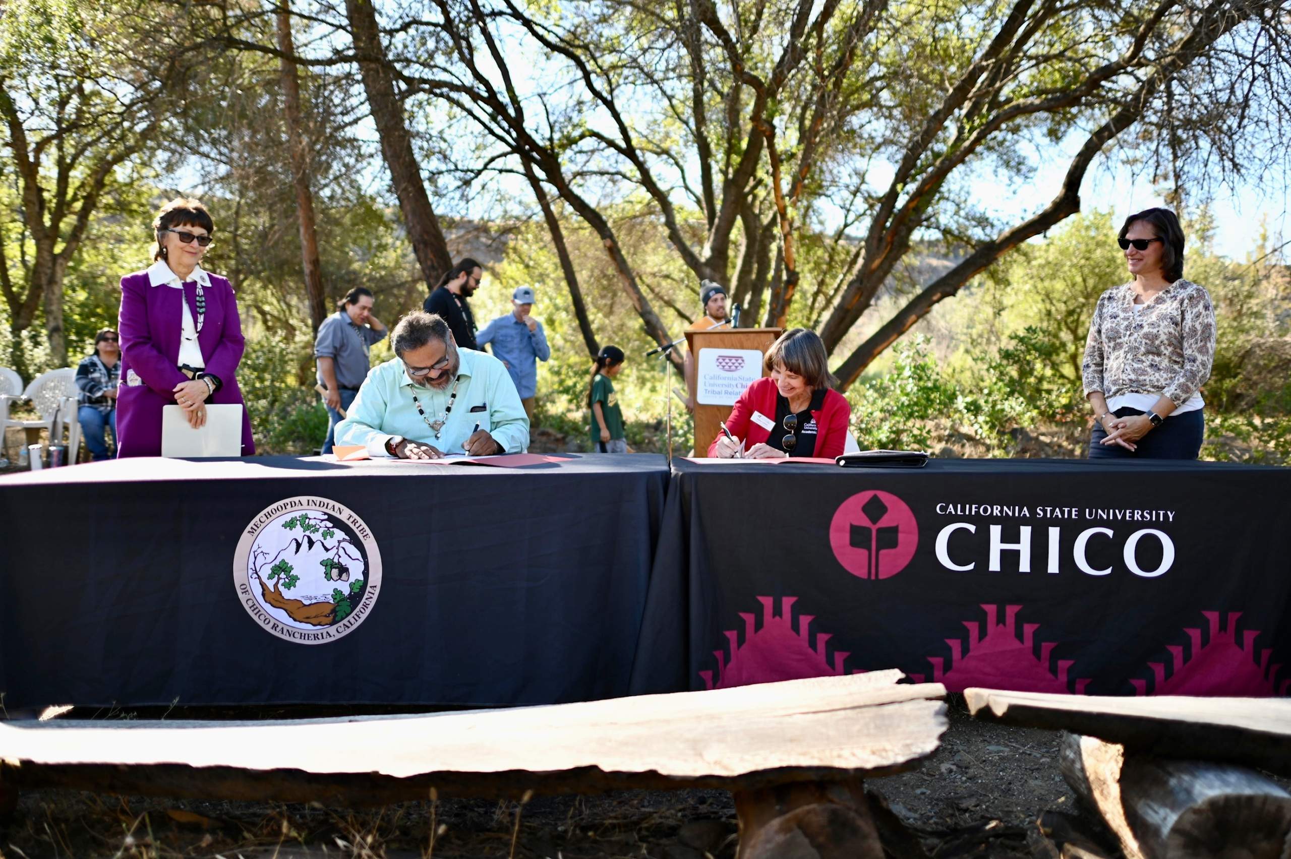 Chico State Provost Debra Larson and Mechoopda Chairman Dennis Ramirez sign documents at a table at the Butte Creek Ecological Preserve