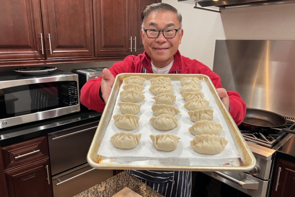 Lance Lew holds out a baking sheet filled with freshly made potstickers