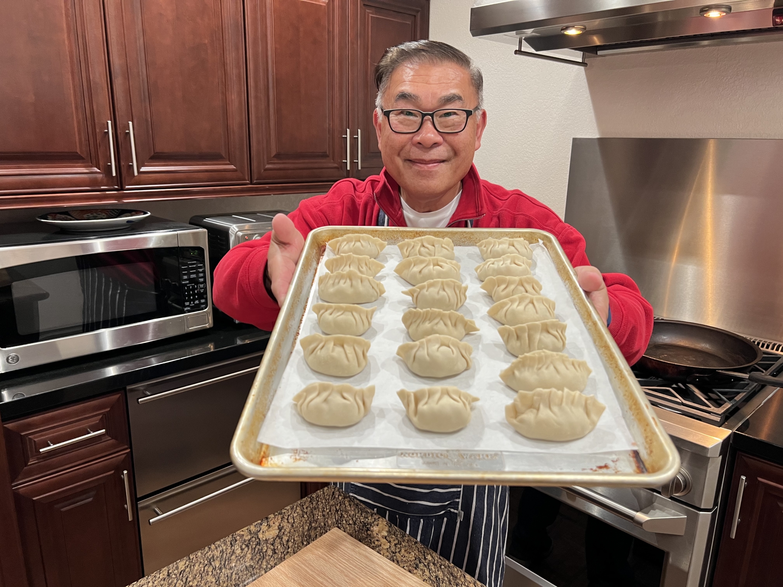 Lance Lew holds out a baking sheet filled with freshly made potstickers