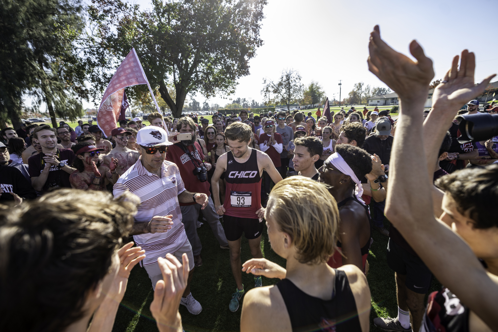 Rory Abberton (middle, wearing bib #93) listens to Head Coach Gary Towne celebratory speech as a number of teammates and fans gather around following the 2019 NCAA Championship race.