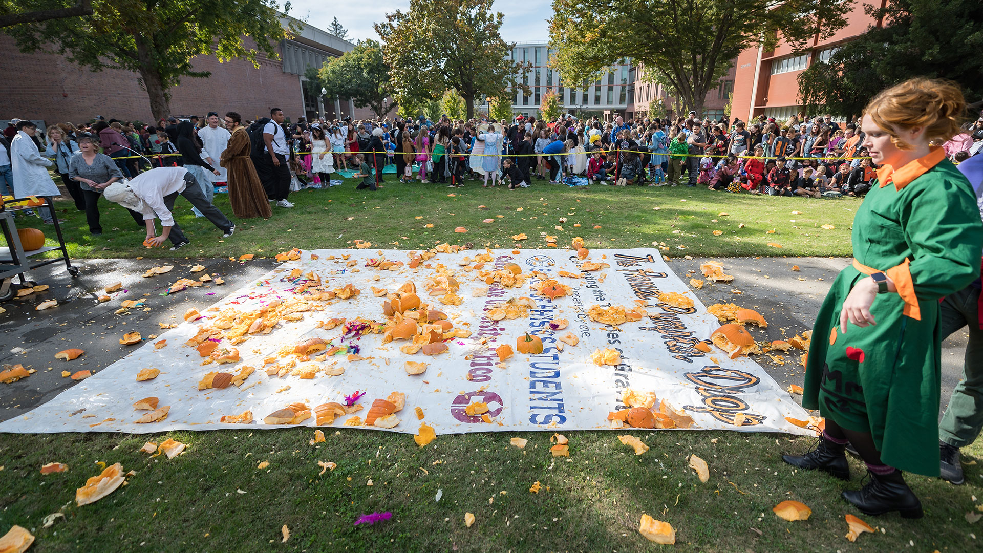 Physics faculty Kendall Hall portrays Ms. Frizzle (right) looks over the smashed pumpkins as local elementary school students watch the Society of Physics students drop pumpkins from a lift during the Annual SPS Pumpkin drop on Monday, October 31, 2022.

