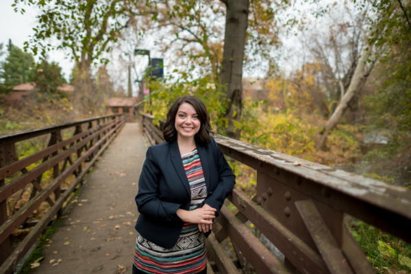 Amy Magnus leans on a pedestrian bridge in a lush, green envirnonment