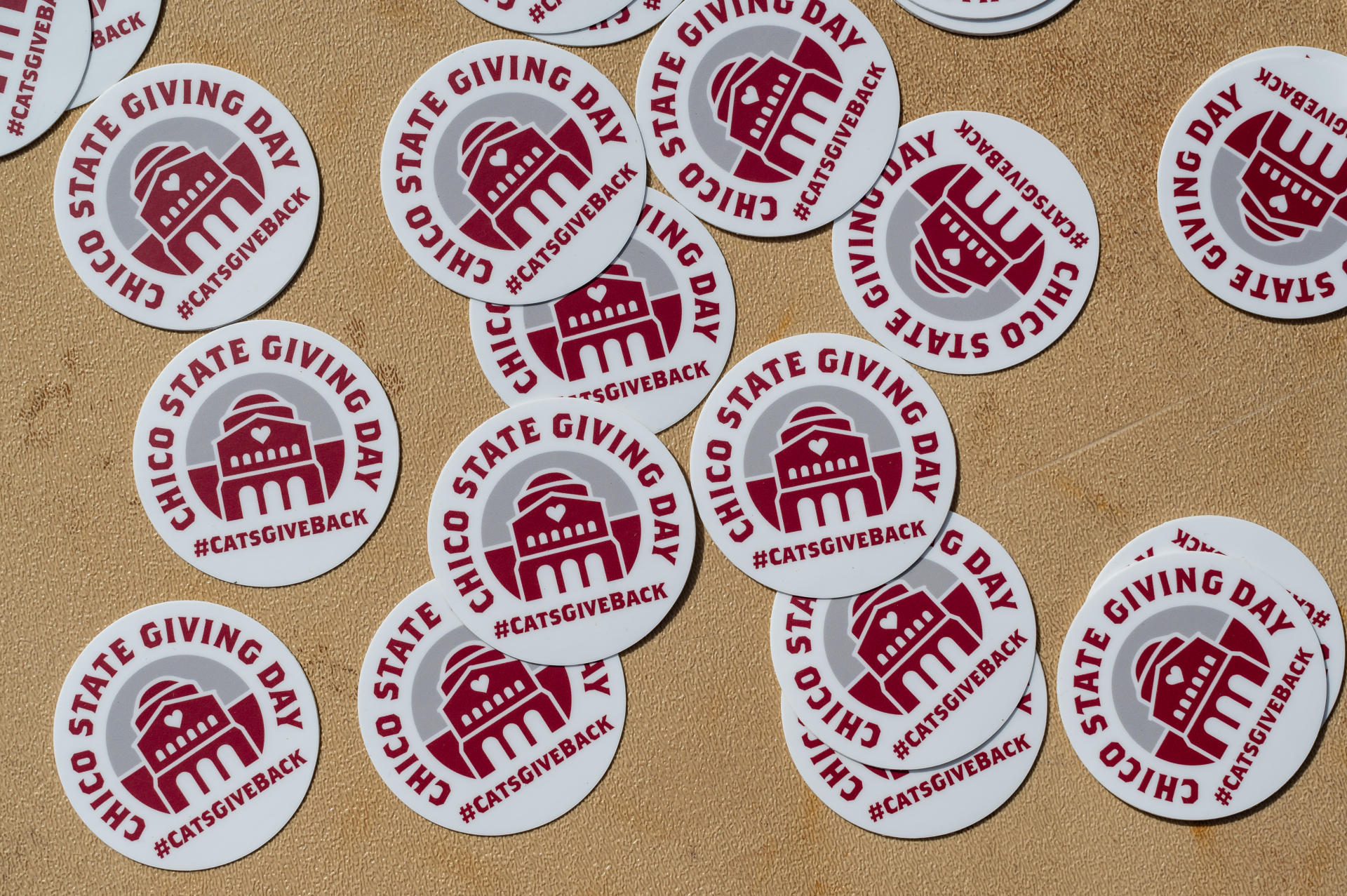 Round stickers that say Chico State Giving Day are spread out on a table