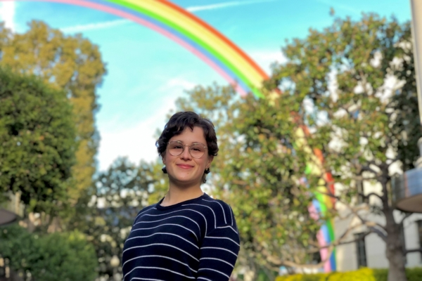 Hannah Hull photographed standing with trees and a rainbow structure in the background.
