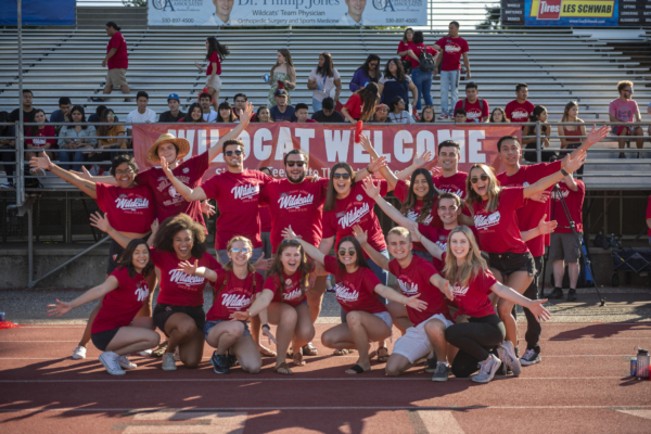 A group of students show excitement and stand in front of a banner that reads 'Wildcat Welcome.' There are bleachers and some students in the background.