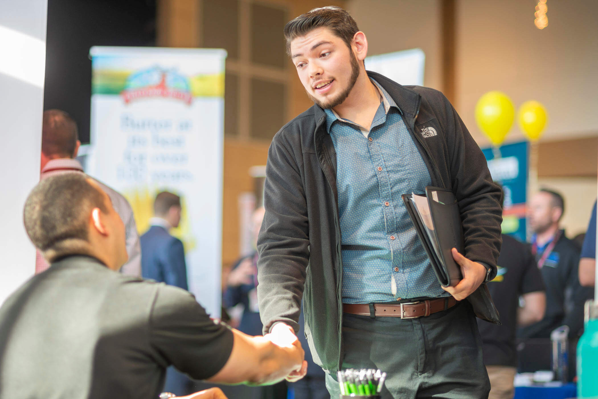 A student shakes a hand of a potential employer at a career fair on campus.