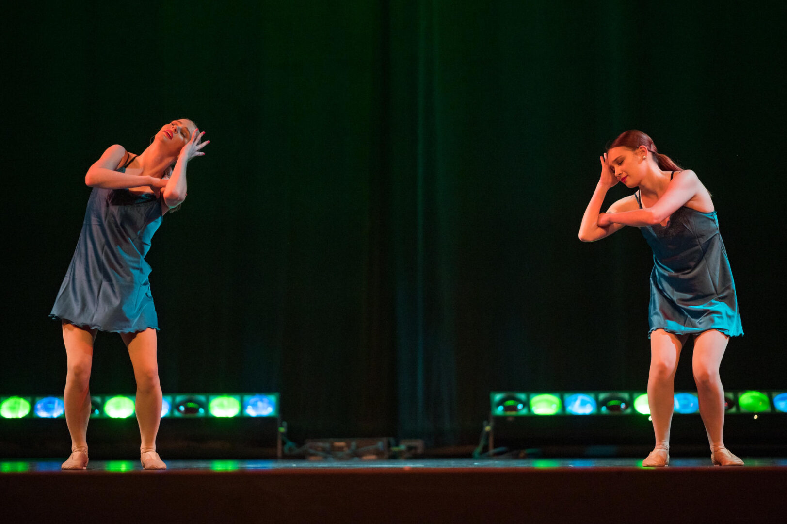 Two female students perform an artistic dance on a stage.