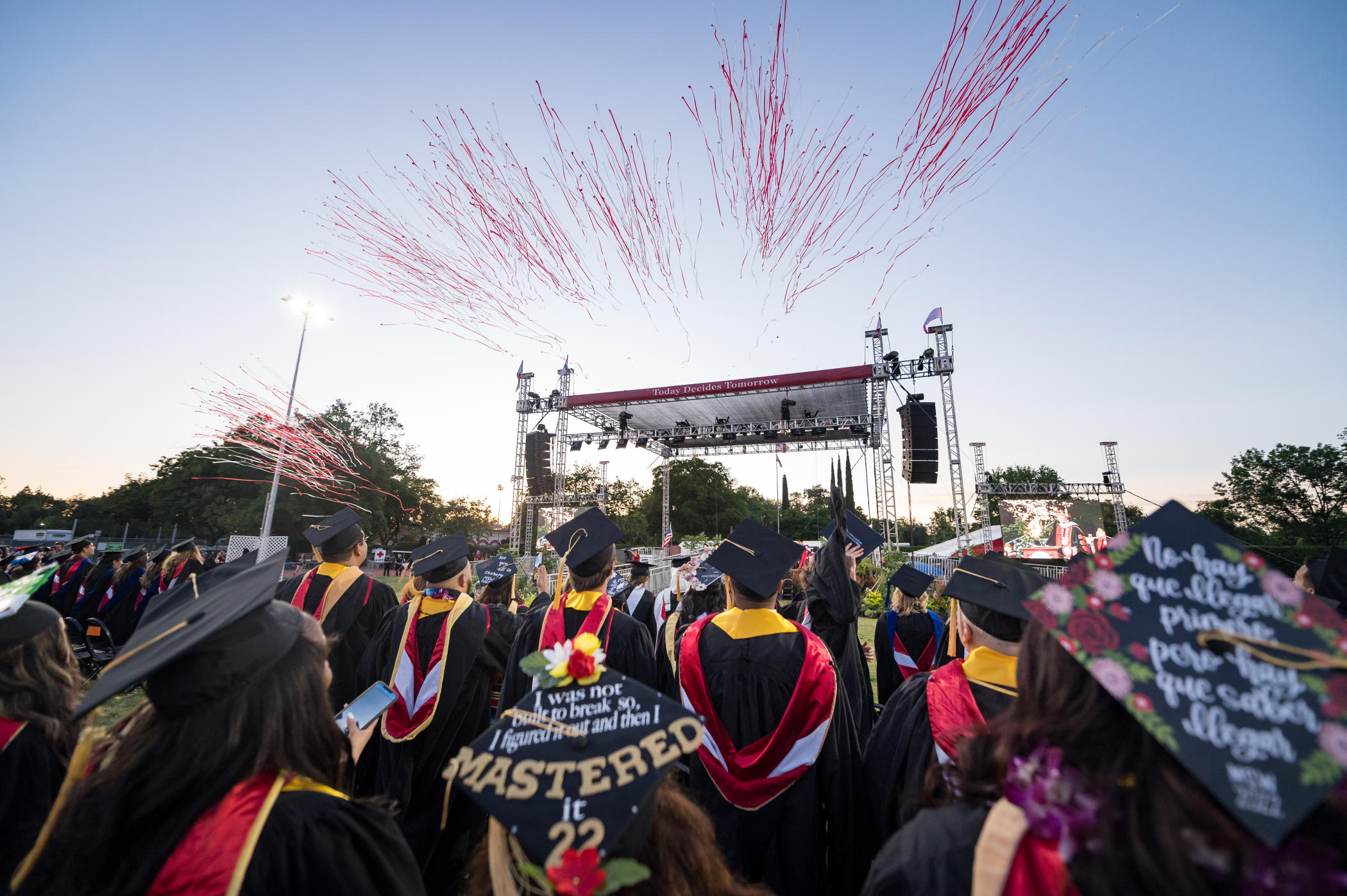 Streamers shoot from atop a stage during an evening Commencement ceremony