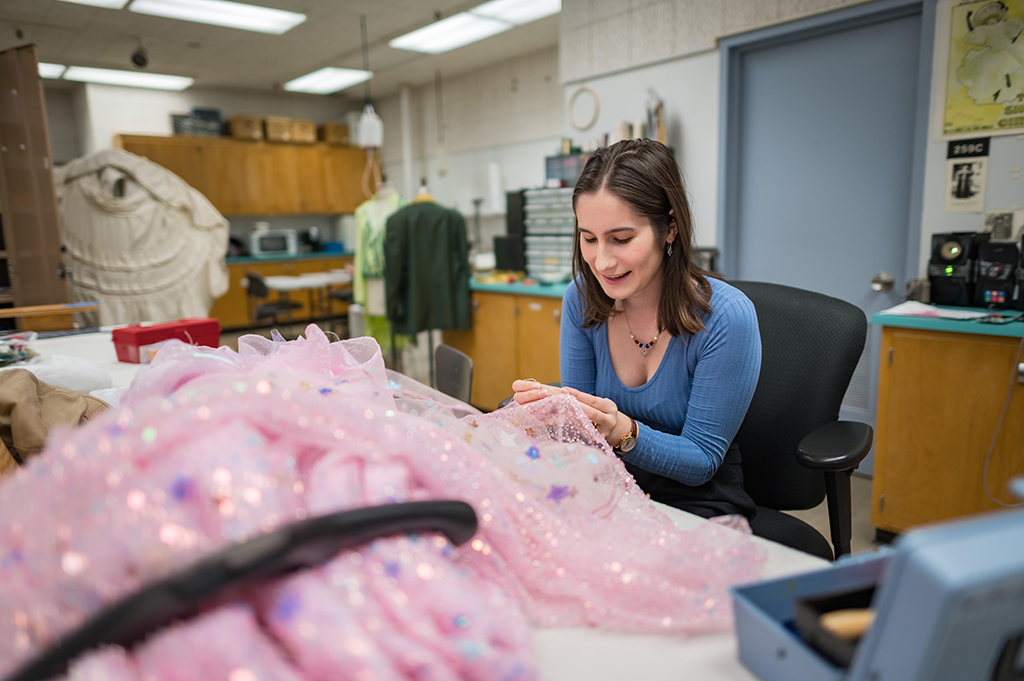 Gaby is stitching together pieces of a pink, starry dress she's working on for the play "The Wizard of Oz."