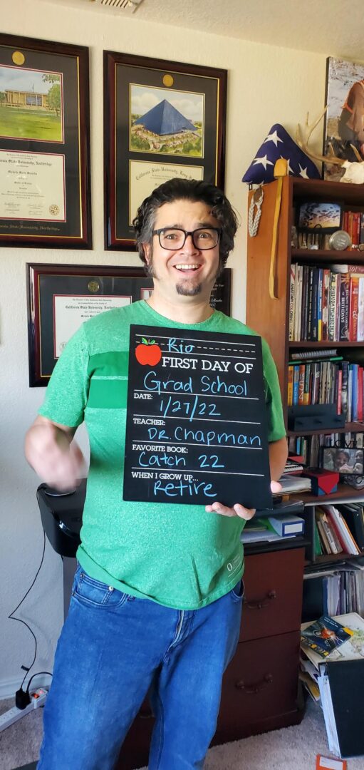 Rio Miner holds a chalkboard on the first day of his graduate school with fun elementary school prompts, including First Day of School, Date, Teacher, Favorite Book, and When I Grow Up