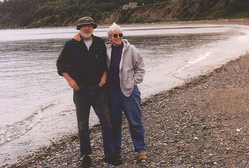 Joel Leonard and his wife stand on a beach.
