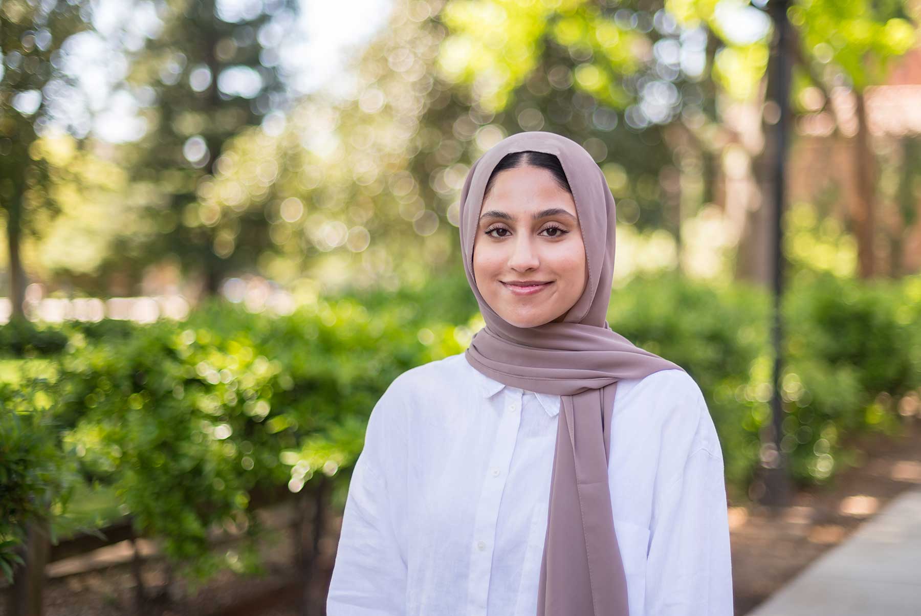 Hirra Khan is photographed outside of Kendall Hall. She wears a white cotton shirt and a tan Hijab.