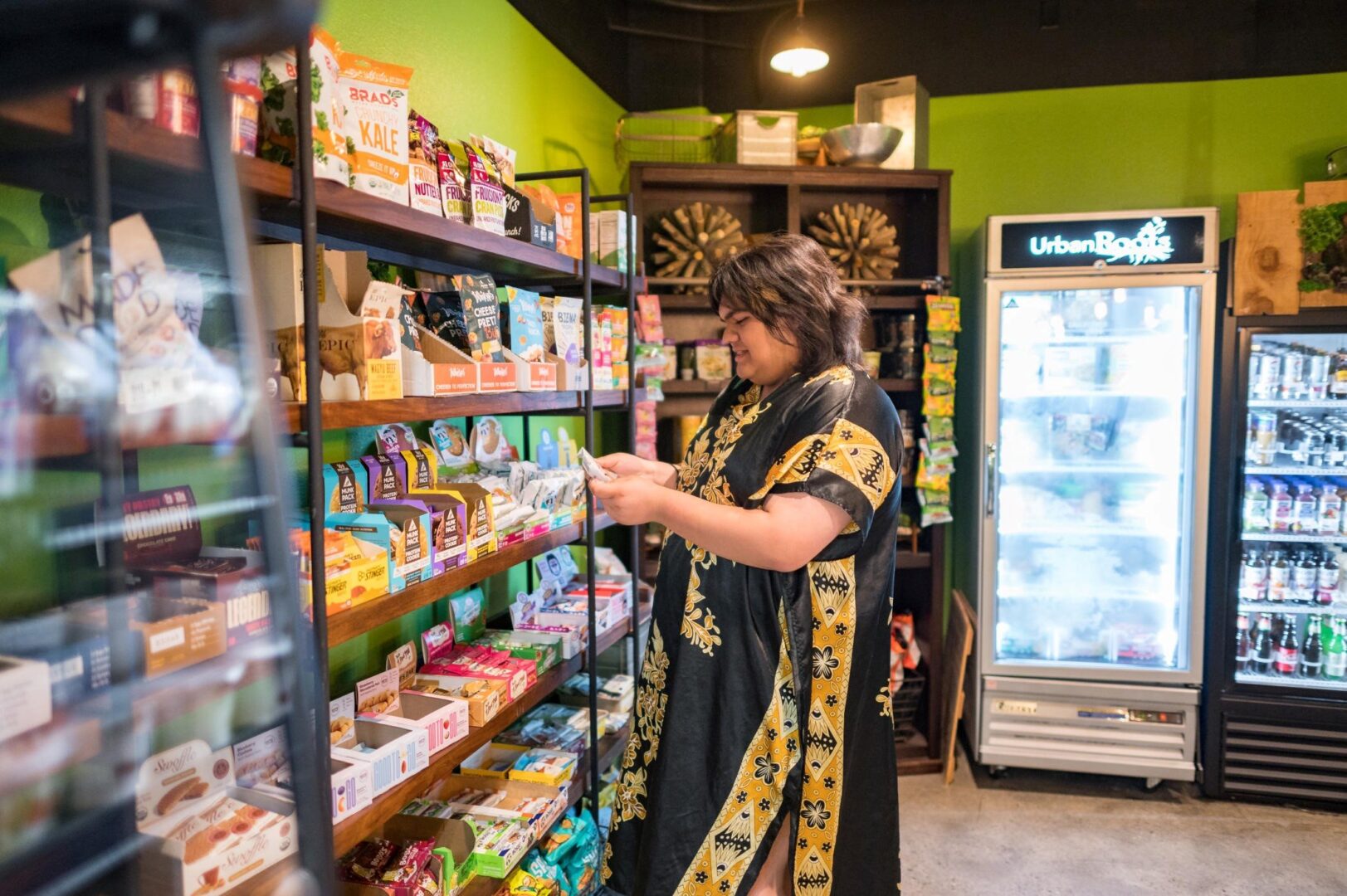Emilio Ceja Guzman stands in front of a display of snacks inside a small market that sells organic, paleo, vegan, and other healthy foods. 