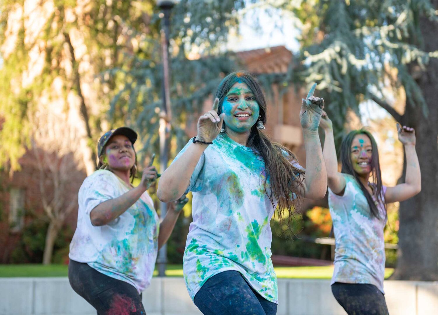 Covered in celebratory paint, Bollywood Dance Club founder,
Aishwarya Gowda, center, performs
with geology major Alinkar Nyein
(right) and public health major
Valinda Arnold (left) at Holi. The Hindu festival of colors,
love, and spring was hosted by the
Cross-Cultural Leadership Center and the Indian Students Association. 