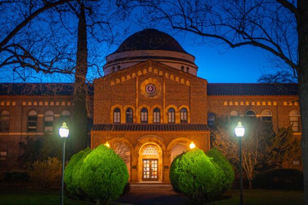 Kendall Hall is photographed at dusk, illuminated by soft lights against a cobalt blue sky.